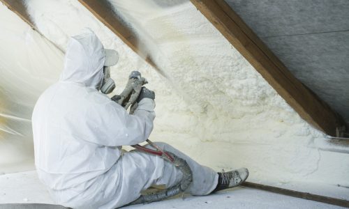 spray polyurethane foam for roof - technician spraying foam insulation using plural component gun for polyurethane foam, inside