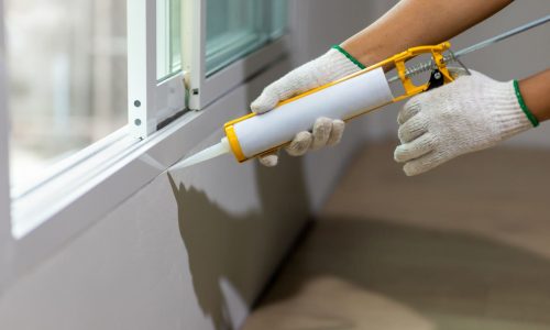 Construction worker using silicone sealant caulk the outside window frame.